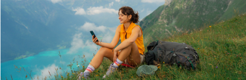 an image of a Woman sitting on the meadow in Swiss Alps using smartphone during the hike